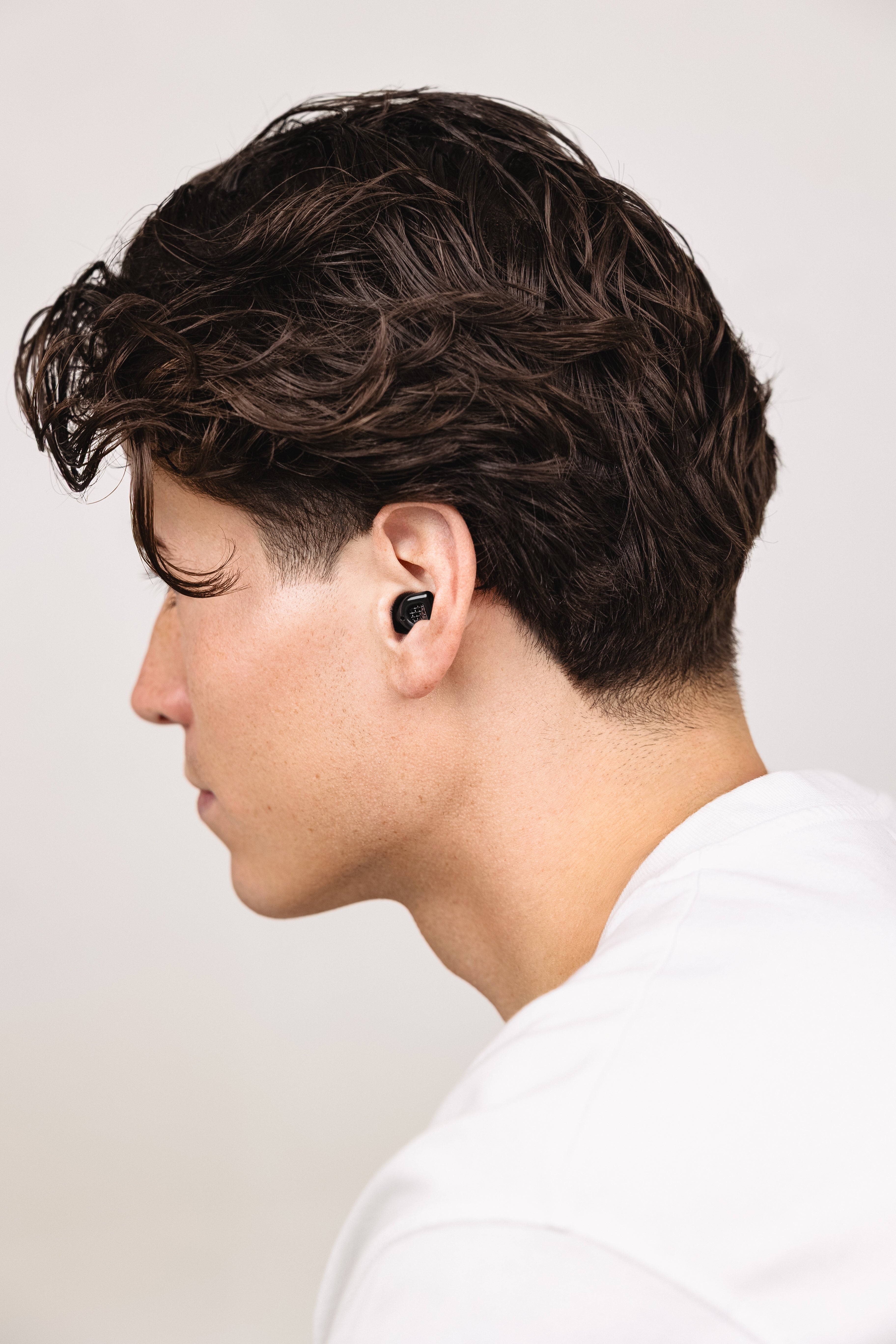 Side profile of a man wearing a black MUSED earplug