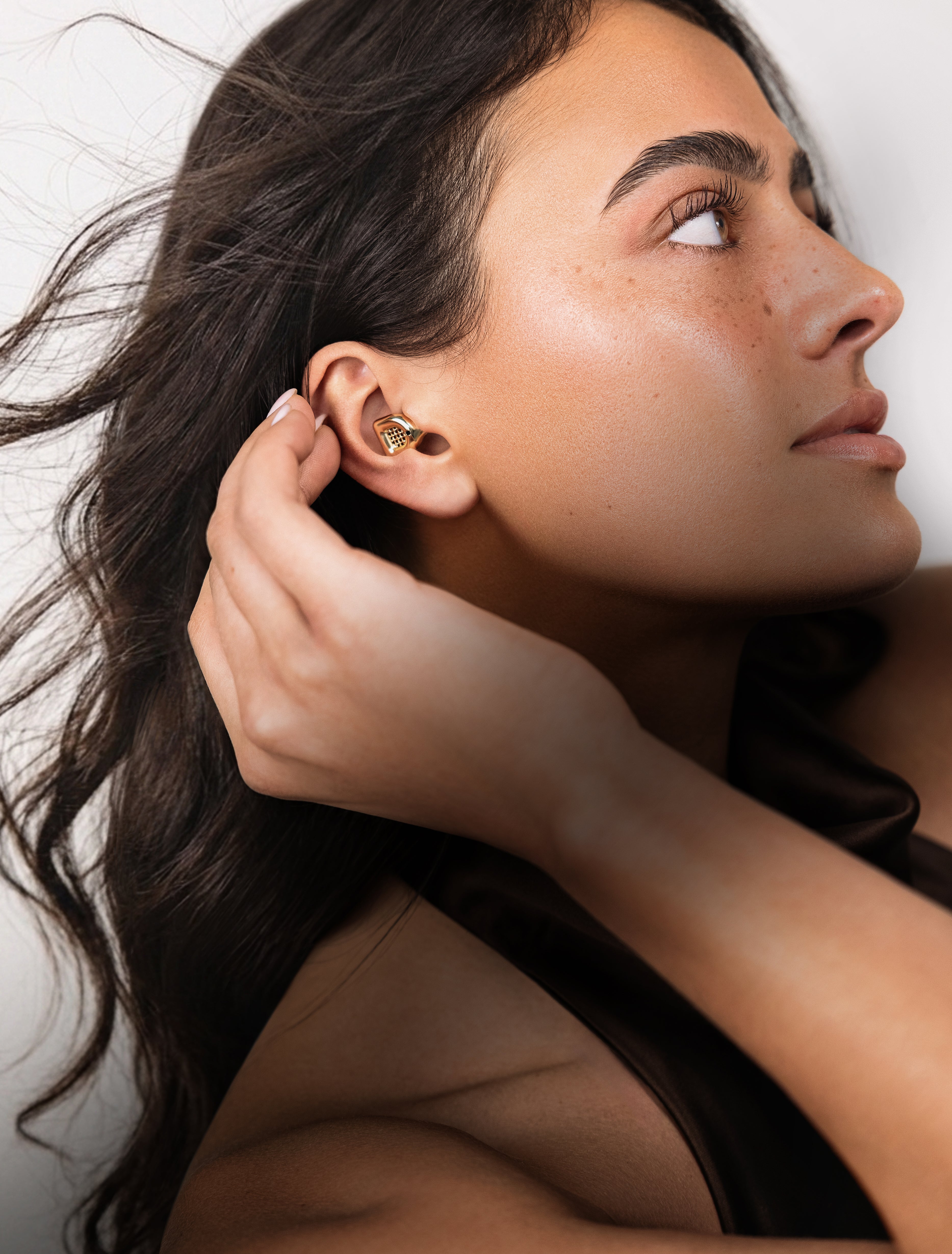 Woman inserting a gold MUSED earplug into her ear
